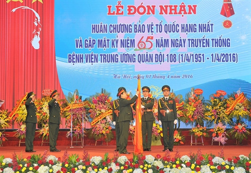 Đại tướng Ngô Xuân Lịch, Ủy viên Bộ Chính trị, Chủ nhiệm Tổng cục Chính trị QĐND Việt Nam; gắn Huân chương Bảo vệ Tổ quốc hạng Nhất lên Cờ truyền thống của Bệnh viện. Ảnh: Trọng Đức – TTXVN