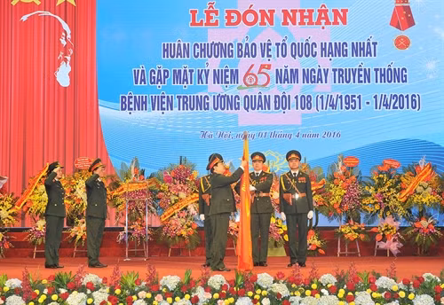 Đại tướng Ngô Xuân Lịch, Ủy viên Bộ Chính trị, Chủ nhiệm Tổng cục Chính trị QĐND Việt Nam; gắn Huân chương Bảo vệ Tổ quốc hạng Nhất lên Cờ truyền thống của Bệnh viện. Ảnh: Trọng Đức – TTXVN