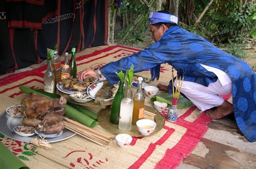 Chủ nhà người Cor thực hiện nghi thức cúng heo chín.