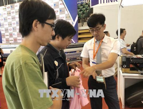 Doanh nghiệp nước ngoài giới thiệu công nghệ in trên sản phẩm may mặc. Ảnh: Mỹ Phương - TTXVN