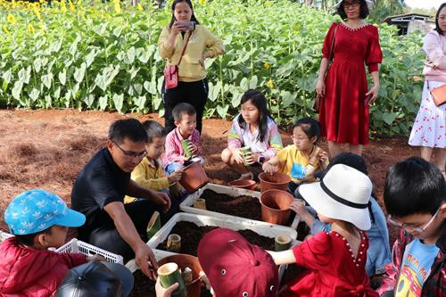 Trẻ em được các hướng dẫn viên nông trại dạy trồng hoa trong ống tre thay vì trong chậu nhựa để bảo vệ môi trường. Trẻ em được các hướng dẫn viên nông trại dạy trồng hoa trong ống tre thay vì trong chậu nhựa để bảo vệ môi trường.