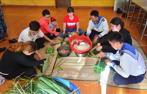 Các cán bộ, chiến sĩ và người dân trên đảo Sinh Tồn gói bánh chưng. Ảnh: Văn Dũng - TTXVN