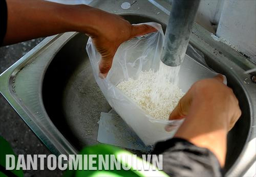 Người dân lấy gạo tuôn ra từ ống nhựa của máy "ATM gạo"