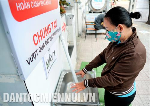 Người lao động nghèo đến nhận gạo chảy ra từ ống nhựa kết nối với thùng gạo được vận hành với công nghệ bán tự động