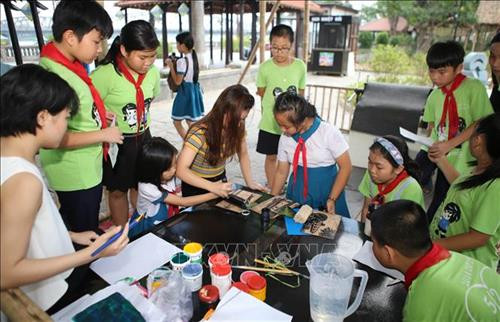 Các em học sinh thích thú với trải nghiệm làm tranh tại không gian triển lãm. Ảnh: Hồ Cầu-TTXVN