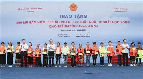 Phó Thủ tướng Chính phủ Vũ Đức Đam và các đại biểu tặng áo phao, học bổng cho các em nhỏ tại buổi lễ. Ảnh: Thanh Tùng-TTXVN