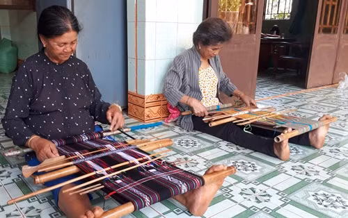 Nghệ nhân An Đê (phải) cùng thành viên dệt thổ cẩm tại nhà. Ảnh: K GỬIH –TTXVN