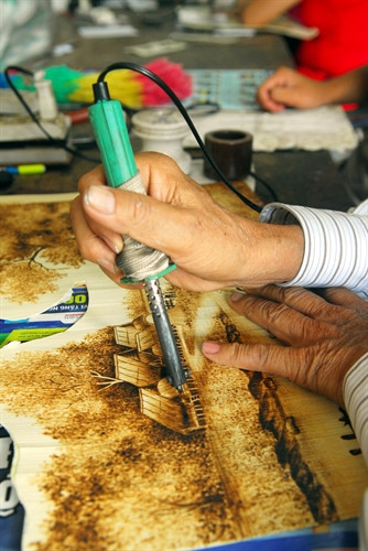 Vẽ tranh trên lá thốt nốt bằng que hàn điện hay còn gọi là “bút lửa”.