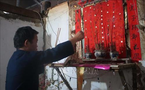 Chủ nhà thắp hương xin phép tổ tiên trước khi đi lấy nước đầu năm mới. Ảnh: Chu Hiệu - TTXVN