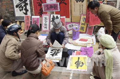 Những năm qua, cứ gần đến Tết Nguyên Đán, tại Hà Nội lại xuất hiện một đoạn " Phố chữ " chạy dọc theo đoạn tường bao cổ kính, rêu phong của Khu di tích Văn Miếu-Quốc Tử Giám. Tại đây, người ta bày bán đủ các thể loại chữ, từ chữ nho đến chữ quốc ngữ được viết trên giấy dó, trên gỗ, trên đá theo kiểu thư pháp. Phố chữ giờ đã đông người "bày mực tàu, giấy đỏ", nhiều người xin chữ với lòng thành kính, góp phần làm đẹp và tăng thêm nét văn hoá của Thủ đô mỗi khi Tết đến Xuân về. Ảnh: Anh Tuấn - TTXVN