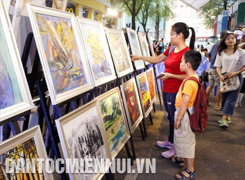 Khách tham quan xem tranh của các họa sĩ khuyết tật trưng bày tại triển lãm