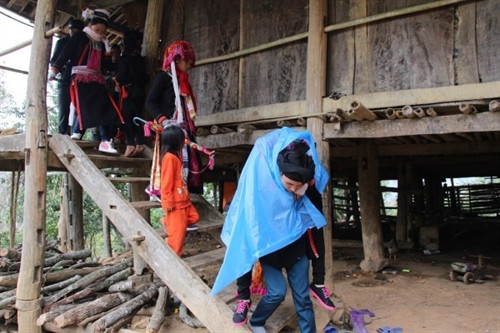 Người thanh niên đưa đón khách của nhà gái cõng cô dâu (phủ khăn xanh) ra cửa. Người thanh niên đưa đón khách của nhà gái cõng cô dâu (phủ khăn xanh) ra cửa.