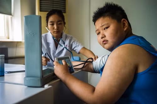 Trong ảnh (tư liệu):Một bé trai bị thừa cân khám bệnh tại bệnh viện điều trị béo phì ở thành phố Thiên Tân (Trung Quốc) ngày 25/5. AFP/TTXVN