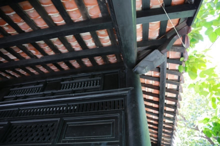 Ngôi nhà cổ được xây từ năm 1799 - Ảnh : Ngọc Tiến. Ngôi nhà được chúa Nguyễn Ánh cho xây dựng vào năm 1799 theo lối kiến trúc truyền thống của Việt Nam với ba gian, hai chái làm nơi trú ngụ cho Giám mục Bá Đa Lộc (quốc tịch Pháp, sinh năm 1741), người dạy học cho hoàng tử Nguyễn Cảnh lúc đó. Ban đầu ngôi nhà được xây dựng bên phần đất của Thảo Cầm Viên bây giờ. Năm 1911, khi Tòa Tổng Giám mục hiện nay được xây dựng hoàn thành, ngôi nhà dời về đây và được giữ gìn, bảo quản đến ngày hôm nay - Ảnh : Ngọc Tiến. Qua những lần di dời trước đó, phần nền đất làm cho cột trụ ngôi nhà bị hư hỏng. Sau đợt trùng tu nền nhà được nâng cao hơn, cột trụ ngôi nhà được đặt trên những tảng đá để đỡ một phần tải trọng và chắc chắn hơn như nguyên bản ngôi nhà ban đầu - Ảnh : Ngọc Tiến. Dàn rui lách, kèo và hệ thống vách được xếp đặt một cách tinh xảo - đó là nét độc đáo và giá trị to lớn về lịch sử và văn hóa ngôi nhà - Ảnh : Ngọc Tiến. Mái nhà được lợp ngói âm dương với những họa tiết hoa văn viền tinh xảo. Hiện nay, lớp ngói đỏ đã được làm mới thay cho lớp ngói cũ rêu phong - Ảnh : Ngọc Tiến. Các cánh cửa làm bằng gỗ quý, hoa văn được điêu khắc tinh xảo tạo thêm nét cổ kính cho mặt tiền của căn nhà - Ảnh : Ngọc Tiến. Ngôi nhà được làm hoàn toàn bằng gỗ quý, khung nhà được liên kết chặt chẽ với nhau hoàn toàn bằng kỹ thuật ghép mộng của những nghệ nhân thời xưa. Hoàn toàn không dùng bất cứ cây đinh nào nhưng ngôi nhà vẫn đứng vững qua hàng trăm năm - Ảnh : Ngọc Tiến. Các nét chạm khắc trên những bộ cửa, vách nhà chưa bị bào mòn và còn nguyên vẹn - Ảnh : Ngọc Tiến. Họa tiết trang trí được khắc họa tỉ mỉ, công phu đặt ngay cửa chính diện tạo sự cân đối và cổ kính, thể hiện nét sáng tạo độc đáo - Ảnh : Ngọc Tiến. Nhiều vật dụng trong nhà như bàn, ghế, tủ, bình phong... vẫn được giữ nguyên vẹn và còn khá tốt. Những chùm đèn được thay mới vì đèn cũ đã hư hỏng, không thể sử dụng được nữa - Ảnh : Ngọc Tiến.