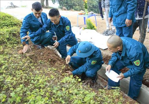 Lực lượng Dân quân tiến hành khai quật hài cốt. Ảnh: Xuân Tư - TTXVN Lực lượng Dân quân tiến hành khai quật hài cốt. Ảnh: Xuân Tư - TTXVN