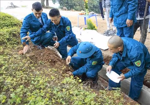 Lực lượng Dân quân tiến hành khai quật hài cốt. Ảnh: Xuân Tư - TTXVN