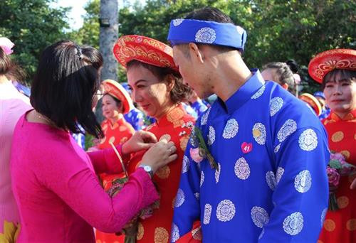 Trao tặng Huy hiệu thành phố cho các cặp đôi tham gia lễ cưới tập thể. Ảnh: Xuân Dự - TTXVN