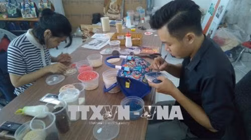 Không khí làm việc tại cơ sở tranh gạo Tấn Bửu. Ảnh: Ánh Tuyết - TTXVN