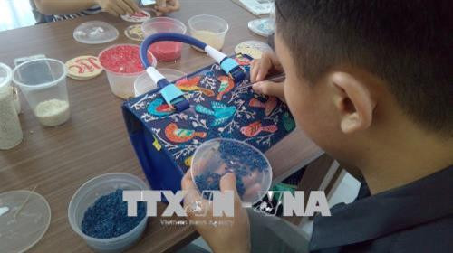 Tấn Bửu đính gạo lên túi xách. Ảnh: Ánh Tuyết - TTXVN Tấn Bửu đính gạo lên túi xách. Ảnh: Ánh Tuyết - TTXVN