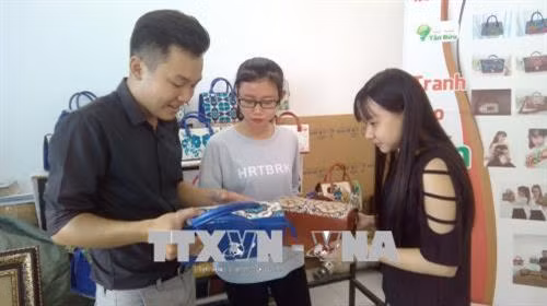 Tấn Bửu (bên trái) đang trao đổi công việc với cộng sự. Ảnh: Ánh Tuyết - TTXVN