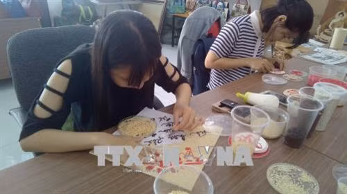 Không khí làm việc tại cơ sở tranh gạo Tấn Bửu. Ảnh: Ánh Tuyết - TTXVN