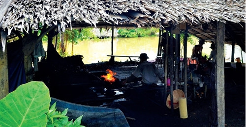 Quang cảnh một lò rèn đỏ lửa bên dòng kênh liên thôn.