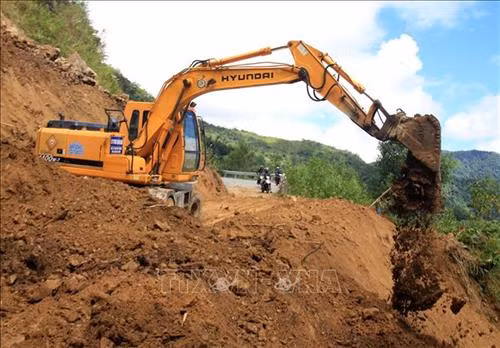 Sở Giao thông vận tải tỉnh Quảng Ngãi huy động phương tiện chuyên dụng san ủi đất đá, thông tuyến để người dân đi lại. Ảnh: Phước Ngọc -TTXVN