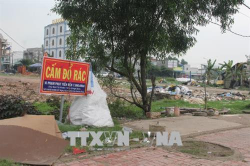 Ngay cạnh tấm biển “Cấm đổ rác” là cả một bãi rác lộ thiên (xã Đức Hòa Hạ, Đức Hòa). Ảnh: Bùi Giang – TTXVN