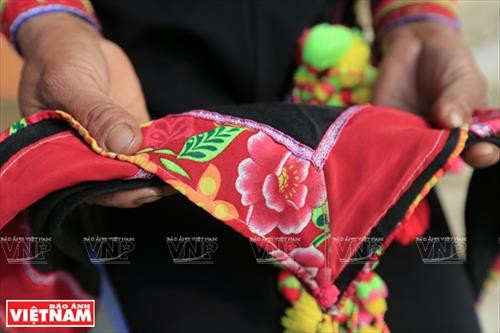 Chiếc vòng làm bằng nhựa màu nâu đỏ dùng để cố định những nếp tóc là lớp đầu tiên của khăn đội đầu người La Hủ. Lớp khăn thứ hai của chiếc khăn đội đầu của những người phụ nữ La Hủ. Nó được làm bằng vài nhiều màu và được gấp lại trước khi đội lên. Người phụ nữ La Hủ cố định lớp thứ 2 của chiếc khăn truyền thống. Sau khi đội lớp thứ 2, họ dùng dải dây thun vấn, che hết phần tóc còn lại. Lớp thứ 3 của chiếc khăn đội đầu có những sợi tua rua dài che phía sau đầu những người phụ nữ La Hủ. Thường từ lớp thứ 3 của chiếc khăn, họ cần một người khác giúp để hoàn thành chiếc khăn đội đầu sao cho đẹp nhất. Dải tua rua là lớp cuối cùng trên chiếc khăn đội đầu. Người con gái La Hủ luôn thường nuôi tóc dài để vấn tóc, đội chiếc khăn truyền thống rất cầu kỳ này. Chiếc khăn đội đầu của người phụ nữ La Hủ nhìn từ phía sau. Hai thế hệ phụ nữ người La Hủ ở Bum Tở. Vào ngày thường phụ nữ La Hủ mặc chiếc áo tà dài có màu đen truyền thống. Nhưng trong dịp lễ họ mặc thêm một chiếc áo khoác ngắn được đính trang trí khá cầu kỳ. Chiếc khăn đội đầu sặc sỡ là điểm nhấn làm nên sự khác biệt trong trang phục của người La Hủ. Những dải tua rua trên chiếc khăn đội đầu tạo nên nét rất sinh động trong trang phục của người phụ nữ La Hủ. Những cô gái La Hủ ở xã Bum Tở, huyện Mường Tè, tỉnh Lai Châu trong trang phục truyền thống đang tập múa, hát trong sân nhà văn hóa của bản.