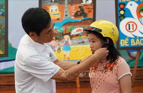 Đại biểu trao mũ bảo hiểm cho các em học sinh. Ảnh: Dư Toán – TTXVN.
