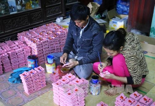 Sơn màu cho tượng ông Công ông Táo. Ảnh: Hồ Câu-TTXVN