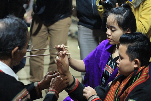 Sau khi khấn tại ché, thầy cúng cầm vòng tay đứng gần hai người kết nghĩa khấn bằng tiếng Ê Đê.