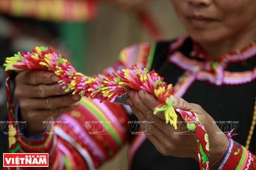 Chiếc vòng làm bằng nhựa màu nâu đỏ dùng để cố định những nếp tóc là lớp đầu tiên của khăn đội đầu người La Hủ. Lớp khăn thứ hai của chiếc khăn đội đầu của những người phụ nữ La Hủ. Nó được làm bằng vài nhiều màu và được gấp lại trước khi đội lên. Người phụ nữ La Hủ cố định lớp thứ 2 của chiếc khăn truyền thống. Sau khi đội lớp thứ 2, họ dùng dải dây thun vấn, che hết phần tóc còn lại. Lớp thứ 3 của chiếc khăn đội đầu có những sợi tua rua dài che phía sau đầu những người phụ nữ La Hủ. Thường từ lớp thứ 3 của chiếc khăn, họ cần một người khác giúp để hoàn thành chiếc khăn đội đầu sao cho đẹp nhất. Dải tua rua là lớp cuối cùng trên chiếc khăn đội đầu. Người con gái La Hủ luôn thường nuôi tóc dài để vấn tóc, đội chiếc khăn truyền thống rất cầu kỳ này. Chiếc khăn đội đầu của người phụ nữ La Hủ nhìn từ phía sau. Hai thế hệ phụ nữ người La Hủ ở Bum Tở. Vào ngày thường phụ nữ La Hủ mặc chiếc áo tà dài có màu đen truyền thống. Nhưng trong dịp lễ họ mặc thêm một chiếc áo khoác ngắn được đính trang trí khá cầu kỳ. Chiếc khăn đội đầu sặc sỡ là điểm nhấn làm nên sự khác biệt trong trang phục của người La Hủ. Những dải tua rua trên chiếc khăn đội đầu tạo nên nét rất sinh động trong trang phục của người phụ nữ La Hủ. Những cô gái La Hủ ở xã Bum Tở, huyện Mường Tè, tỉnh Lai Châu trong trang phục truyền thống đang tập múa, hát trong sân nhà văn hóa của bản.