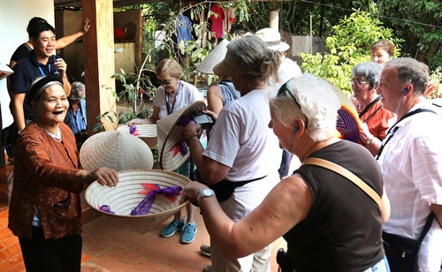 Nghệ nhân làng nghề làm nón Gia Thanh, huyện Phù Ninh tặng nón cho du khách tham quan.