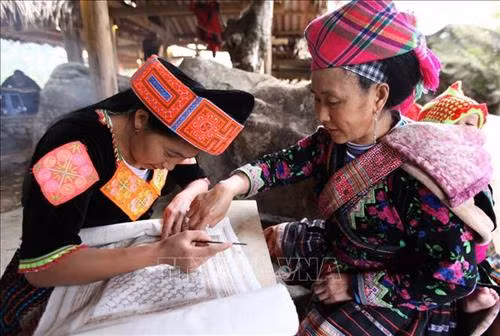 Hướng dẫn học viên kỹ thuật vẽ hoa văn trên vải bằng sáp ong của người Mông. Ảnh: Quý Trung – TTXVN