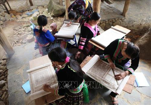 Hướng dẫn học viên kỹ thuật vẽ hoa văn trên vải bằng sáp ong của người Mông. Ảnh: Quý Trung – TTXVN Hướng dẫn học viên kỹ thuật vẽ hoa văn trên vải bằng sáp ong của người Mông. Ảnh: Quý Trung – TTXVN