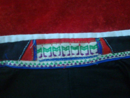 Mô típ trang trí hình chữ M cách điệu trên cổ áo nữ Mông đen.