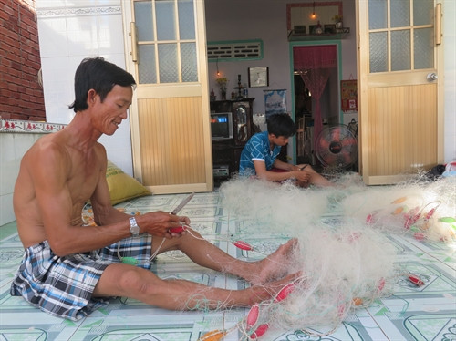 Ngư dân vá lưới chuẩn bị cho ngày ra khơi. Ảnh: Thạch RoBer