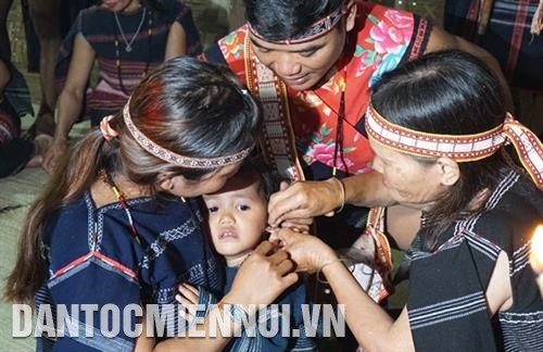 Bà đỡ thực hiện nghi thức xỏ lỗ tai cho em bé. Ảnh: Hoàng Hải