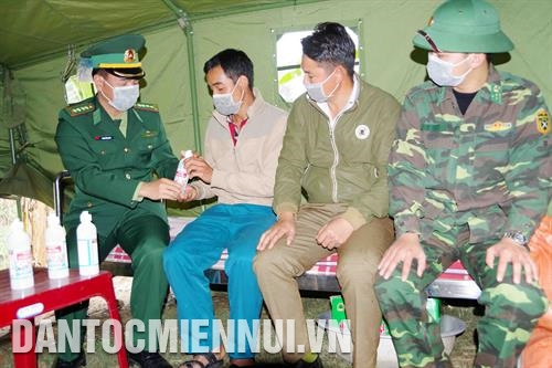 Cán bộ Bộ đội Biên phòng tỉnh Lai Châu tặng và hướng dẫn người dân vùng biên cách sử dụng nước sát khuẩn. Ảnh: Công Tuyên