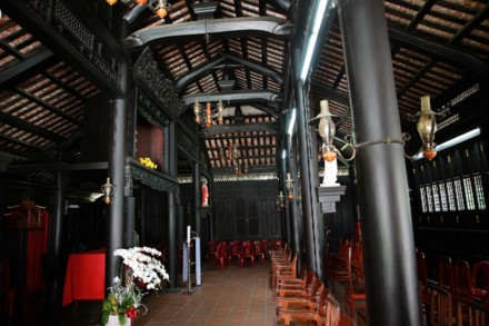 Ngôi nhà cổ được xây từ năm 1799 - Ảnh : Ngọc Tiến. Ngôi nhà được chúa Nguyễn Ánh cho xây dựng vào năm 1799 theo lối kiến trúc truyền thống của Việt Nam với ba gian, hai chái làm nơi trú ngụ cho Giám mục Bá Đa Lộc (quốc tịch Pháp, sinh năm 1741), người dạy học cho hoàng tử Nguyễn Cảnh lúc đó. Ban đầu ngôi nhà được xây dựng bên phần đất của Thảo Cầm Viên bây giờ. Năm 1911, khi Tòa Tổng Giám mục hiện nay được xây dựng hoàn thành, ngôi nhà dời về đây và được giữ gìn, bảo quản đến ngày hôm nay - Ảnh : Ngọc Tiến. Qua những lần di dời trước đó, phần nền đất làm cho cột trụ ngôi nhà bị hư hỏng. Sau đợt trùng tu nền nhà được nâng cao hơn, cột trụ ngôi nhà được đặt trên những tảng đá để đỡ một phần tải trọng và chắc chắn hơn như nguyên bản ngôi nhà ban đầu - Ảnh : Ngọc Tiến. Dàn rui lách, kèo và hệ thống vách được xếp đặt một cách tinh xảo - đó là nét độc đáo và giá trị to lớn về lịch sử và văn hóa ngôi nhà - Ảnh : Ngọc Tiến. Mái nhà được lợp ngói âm dương với những họa tiết hoa văn viền tinh xảo. Hiện nay, lớp ngói đỏ đã được làm mới thay cho lớp ngói cũ rêu phong - Ảnh : Ngọc Tiến. Các cánh cửa làm bằng gỗ quý, hoa văn được điêu khắc tinh xảo tạo thêm nét cổ kính cho mặt tiền của căn nhà - Ảnh : Ngọc Tiến. Ngôi nhà được làm hoàn toàn bằng gỗ quý, khung nhà được liên kết chặt chẽ với nhau hoàn toàn bằng kỹ thuật ghép mộng của những nghệ nhân thời xưa. Hoàn toàn không dùng bất cứ cây đinh nào nhưng ngôi nhà vẫn đứng vững qua hàng trăm năm - Ảnh : Ngọc Tiến. Các nét chạm khắc trên những bộ cửa, vách nhà chưa bị bào mòn và còn nguyên vẹn - Ảnh : Ngọc Tiến. Họa tiết trang trí được khắc họa tỉ mỉ, công phu đặt ngay cửa chính diện tạo sự cân đối và cổ kính, thể hiện nét sáng tạo độc đáo - Ảnh : Ngọc Tiến. Nhiều vật dụng trong nhà như bàn, ghế, tủ, bình phong... vẫn được giữ nguyên vẹn và còn khá tốt. Những chùm đèn được thay mới vì đèn cũ đã hư hỏng, không thể sử dụng được nữa - Ảnh : Ngọc Tiến.