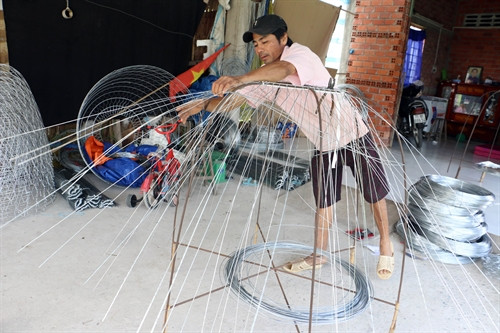 Mỗi ngày vợ chồng anh Nguyễn Trung Nam, ấp Hòa An, xã Long Thới đan được khoảng 15 chiếc bội kẽm, thu nhập khoảng 6-7 triệu đồng/tháng. Ảnh : Trần Thị Thu Hiền – TTXVN