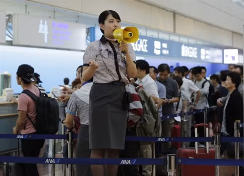 Nhân viên hàng không hướng dẫn hành khách tại sân bay quốc tế Tokyo ở Haneda, thủ đô Tokyo, ngày 20/9. EPA/TTXVN