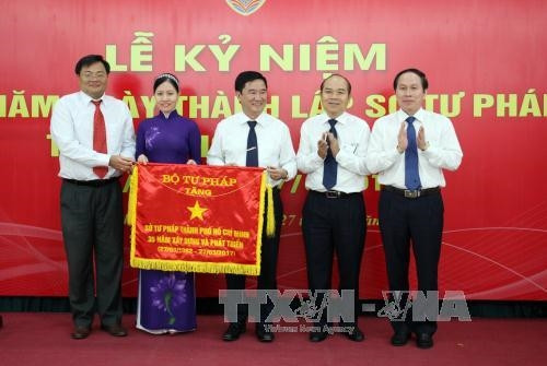 Thứ trưởng Bộ Tư pháp Lê Tiến Châu (ngoài cùng bên phải) trao tặng Cờ của Bộ Tư pháp cho Sở Tư pháp Thành phố Hồ Chí Minh nhân kỷ niệm 35 năm Ngày thành lập. Ảnh: Mạnh Linh-TTXVN