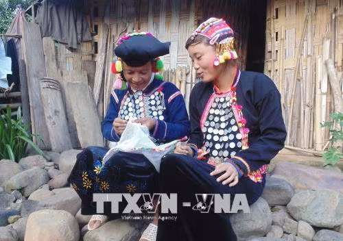 Người Si La truyền dạy cách thêu thùa, tạo hoa văn trên trang phục truyền thống của dân tộc cho con cháu trong bản. Ảnh: Xuân Tiến-TTXVN