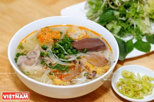 Bún bò Huế ăn cùng với mấy cọng rau húng thơm, chút hoa chuối thái mỏng, mấy múi chanh giấy (chanh cốm) thơm lừng và đặc biệt là ớt xanh của Huế.