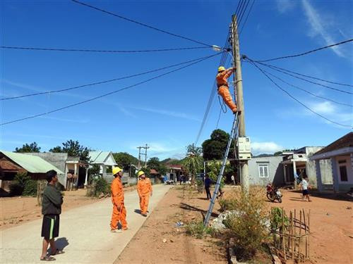 Đoàn viên Công ty Điện lực Kon Tum lắp đặt hệ thống đèn chiếu sáng tại làng Đăk Tum. Ảnh: Cao Nguyên - TTXVN