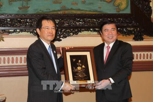 Chủ tịch UBND Thành phố Hồ Chí Minh Nguyễn Thành Phong tặng quà lưu niệm Chủ tịch Phòng Thương mại và Công nghiệp Osaka – Nhật Bản Hiroshi Ozaki. Ảnh: Thanh Vũ-TTXVN