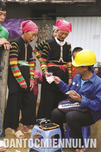 Người Lô Lô ở xã Hồng Trị thanh toán tiền điện cho nhân viên ngành điện huyện Bảo Lạc. Ảnh: An Thành Đạt