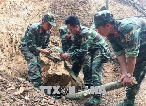 Các Chiến sĩ tiến hành tháo gỡ quả quả bom. Ảnh: Xuân Tư – TTXVN